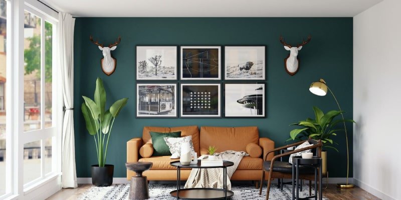 A modern living room featuring a green wall with framed art, burnt orange sofa, gold floor lamp, and lush indoor plants.
