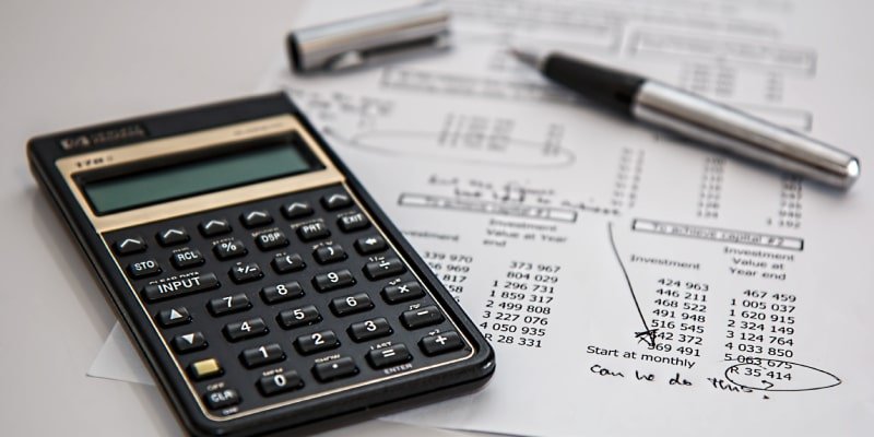 A financial desk setup featuring a TI-30Xa calculator, silver pen, and printed investment documents with handwritten notes and circled figures.