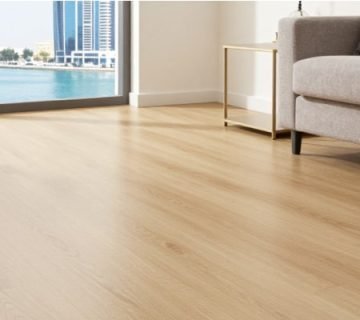 A bright Dubai living room with SPC wood-look flooring, beige sofa, and Marina skyline view—emphasizing waterproof performance and aesthetic appeal in the best flooring for Dubai apartments.