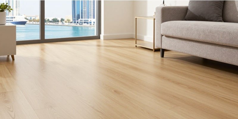 A bright Dubai living room with SPC wood-look flooring, beige sofa, and Marina skyline view—emphasizing waterproof performance and aesthetic appeal in the best flooring for Dubai apartments.